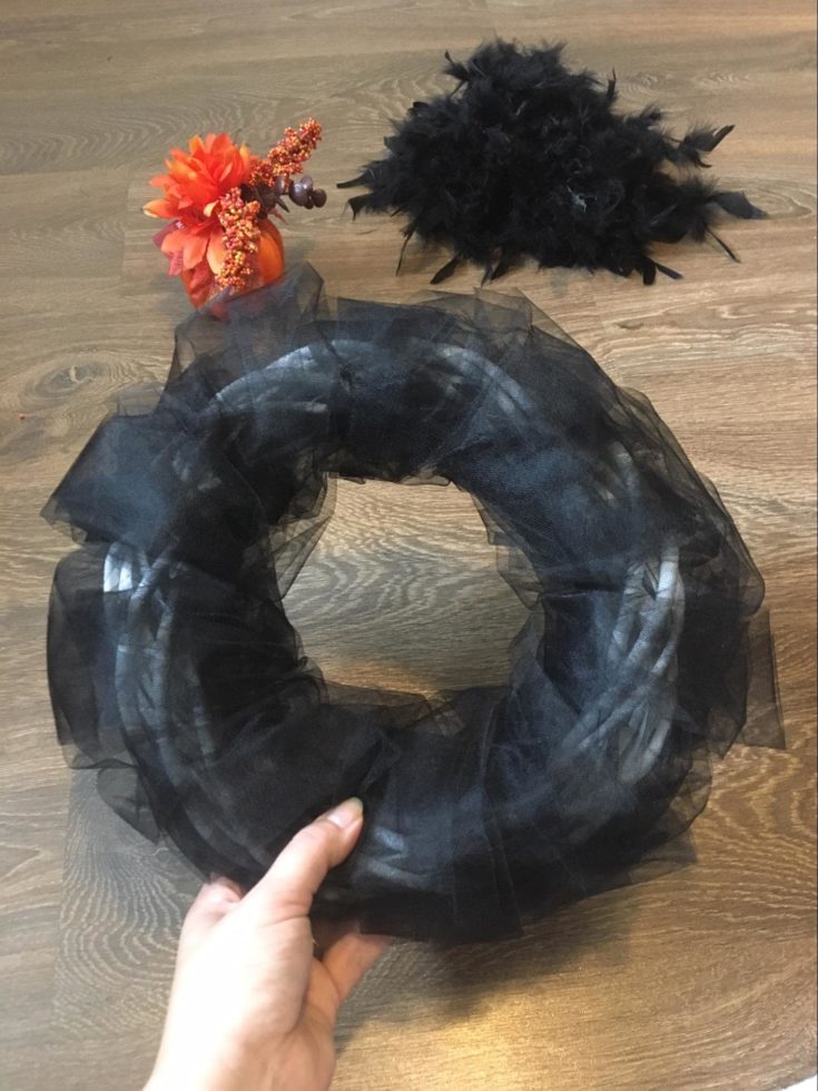 a hand holding a Wicker wreath completely wrapped with black fabric