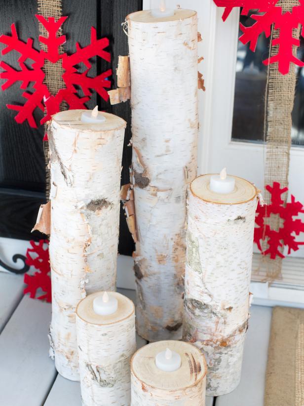 White wood log luminaries with red snowflakes cut out in the background