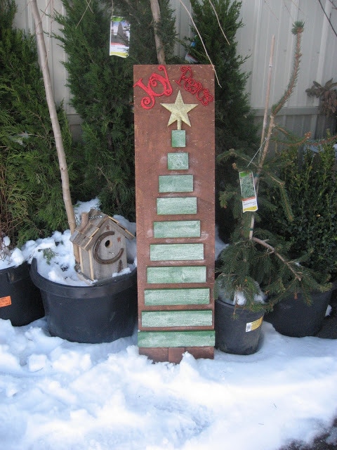 Cut wooden planks form as Christmas tree on brown wood with Joy Peace written on top