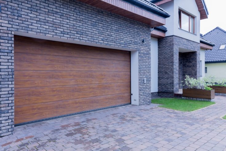 View of wooden garage door and main entrance of detached house