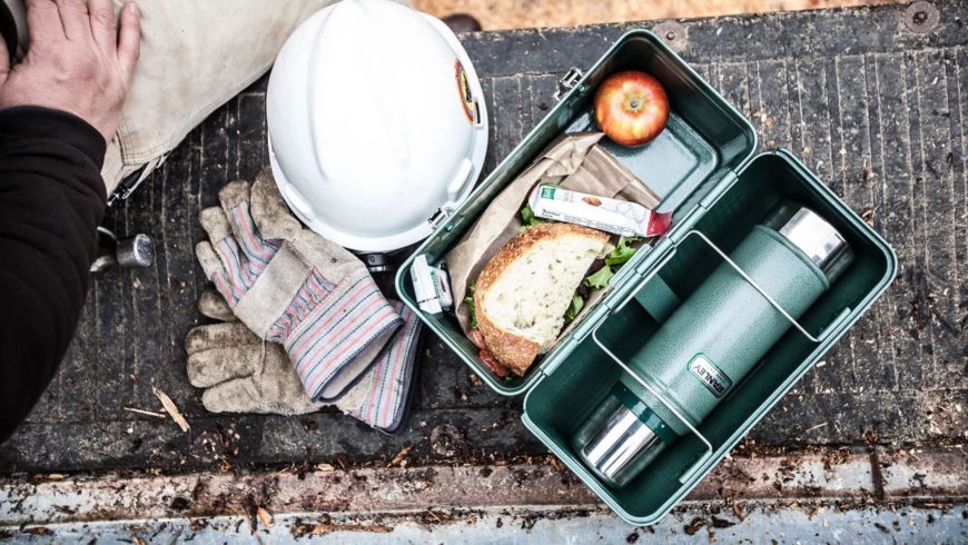Crop shot of lunch box with a man and protective gears beside.