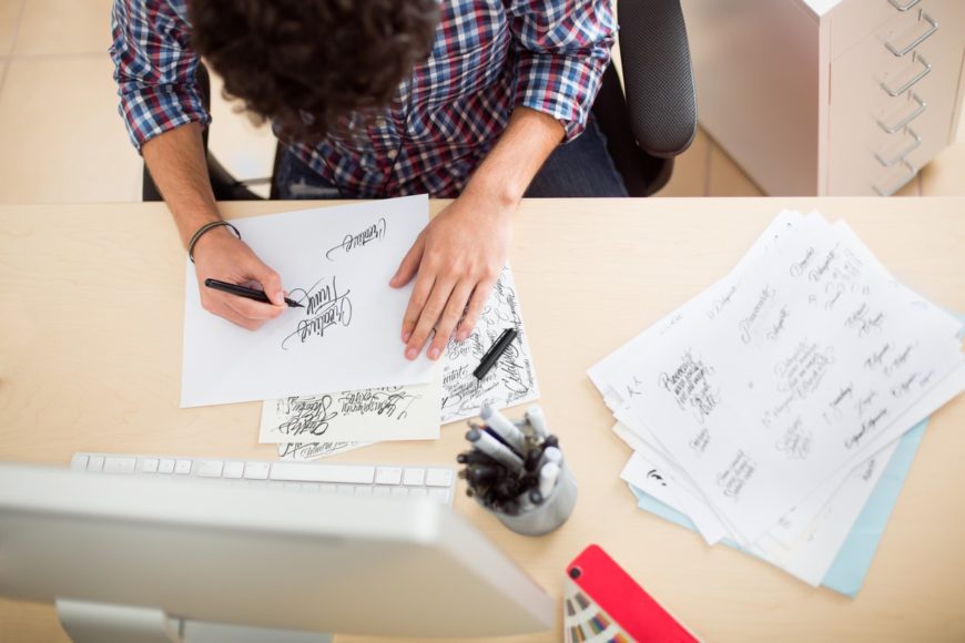 Man sitting down doing calligraphy on his office table