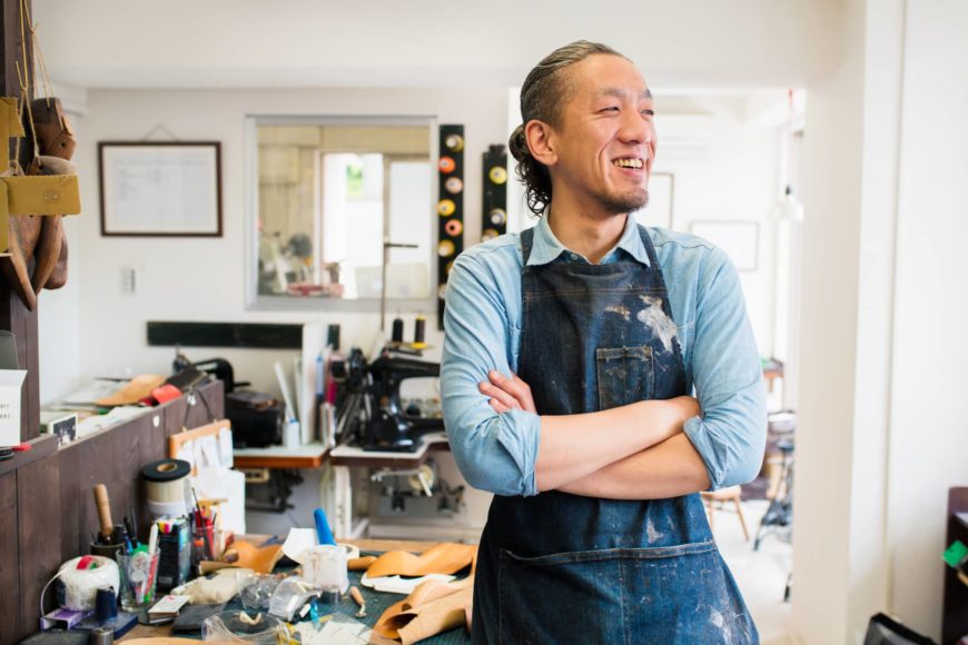 Man standing and smiling with art materials at the back