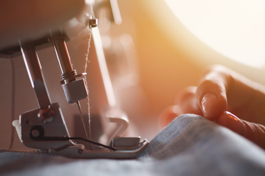 Close up shot of sewing machine needle, cloth and person's hand