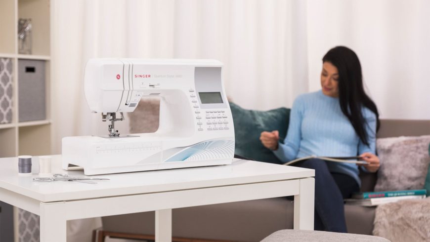 Sewing machine on the table and a woman sitting on the couch at the back