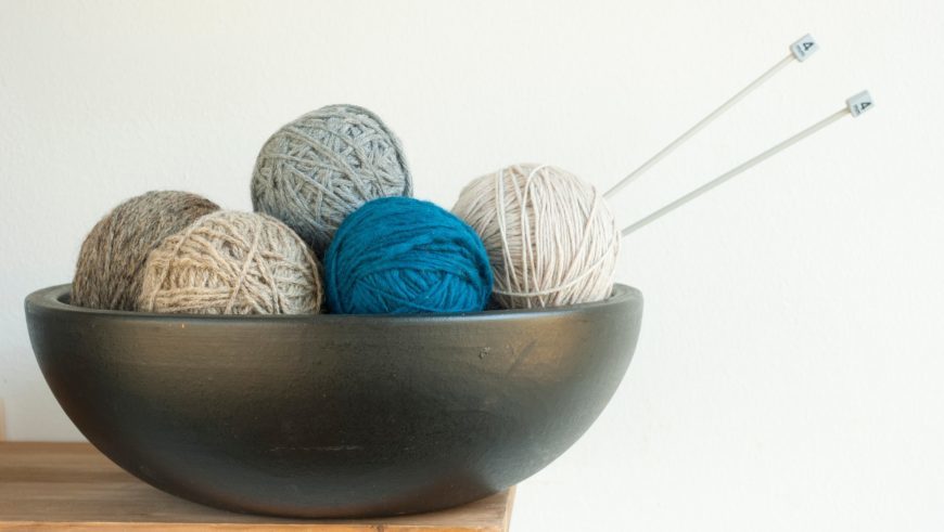 Yarns on bowl at the top of wooden corner in white background