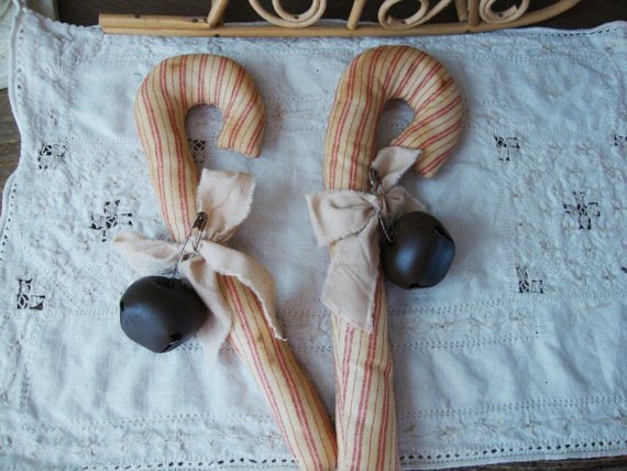 Cane wrapped in striped fabric with black bell on top of white cloth