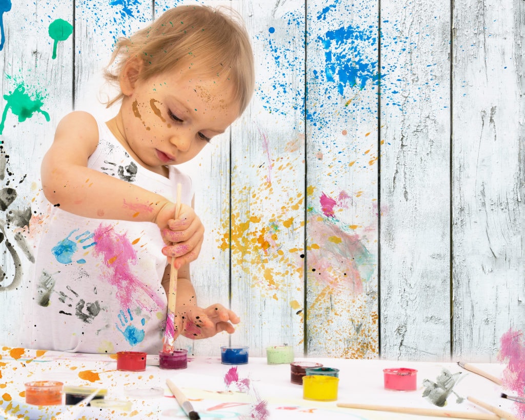 Two-year old girl paints with poster paintings.