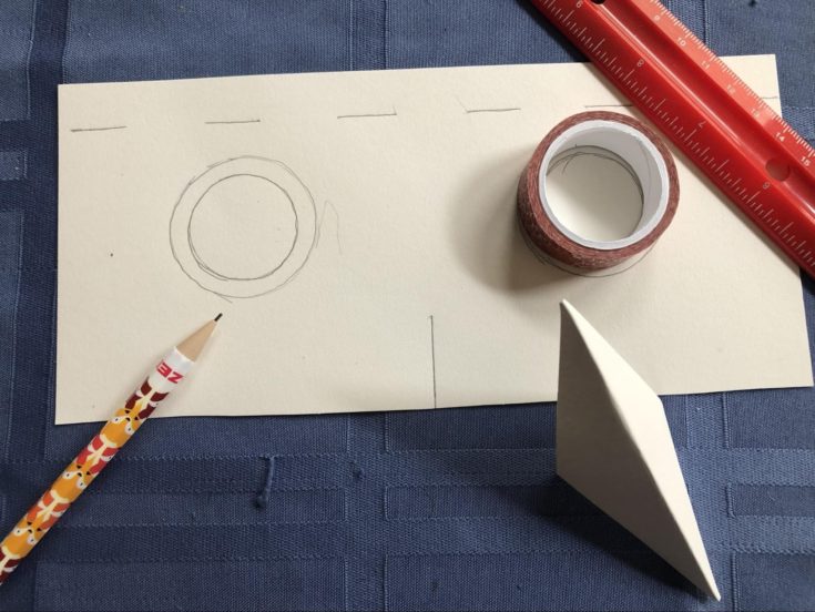 eyes cutouts on a mask with pencil and ruler