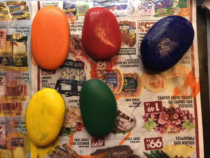 Smooth stones painted with red,blue,green,yellow and orange acrylic paint.