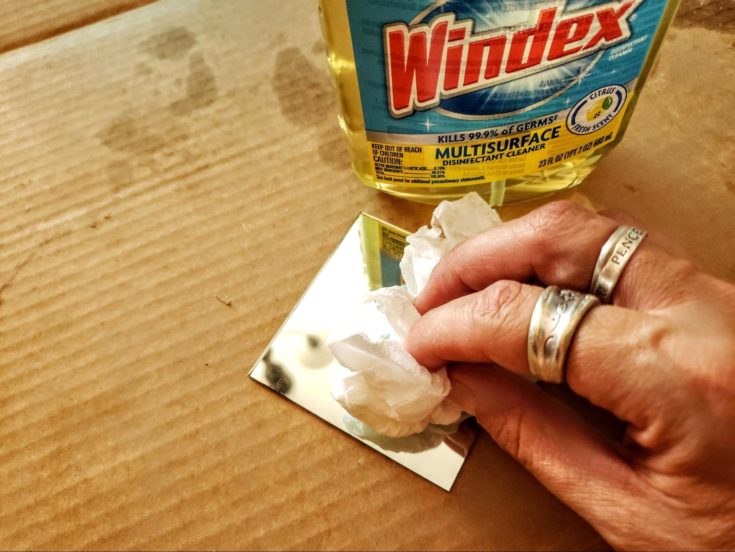 Woman hand's wiping the mirror glass with towel tissue.