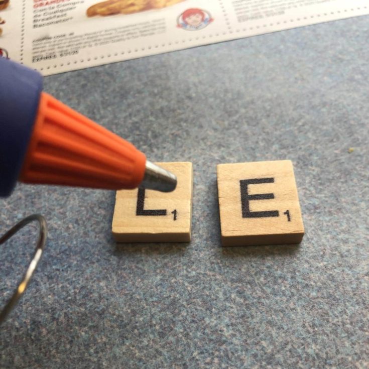 Applying glue to letter L and E of scrabble.