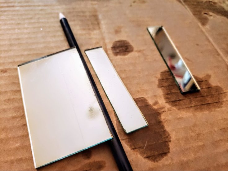 Wooden pencil in between line of the scored mirror glass and the split mirror glass.