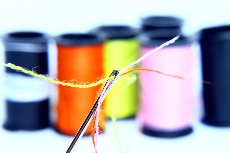 needle with thread, colorful threads at the back