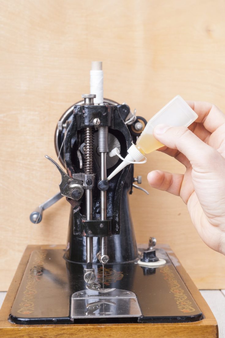 repairman lubricating oil the mechanism of the sewing machine