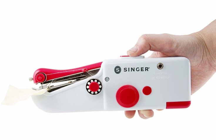 Singer handheld sewing machine with white cloth ready for sewing.