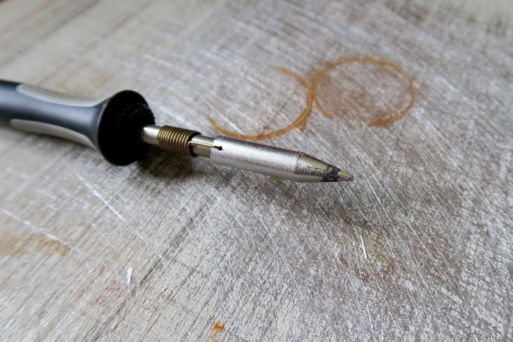 Closeup view soldering iron laid on wooden table.