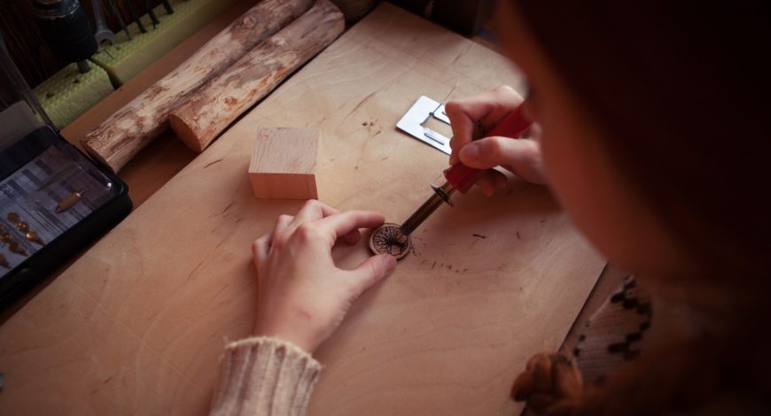 Girl doing wood burning on table with round small woods on her front